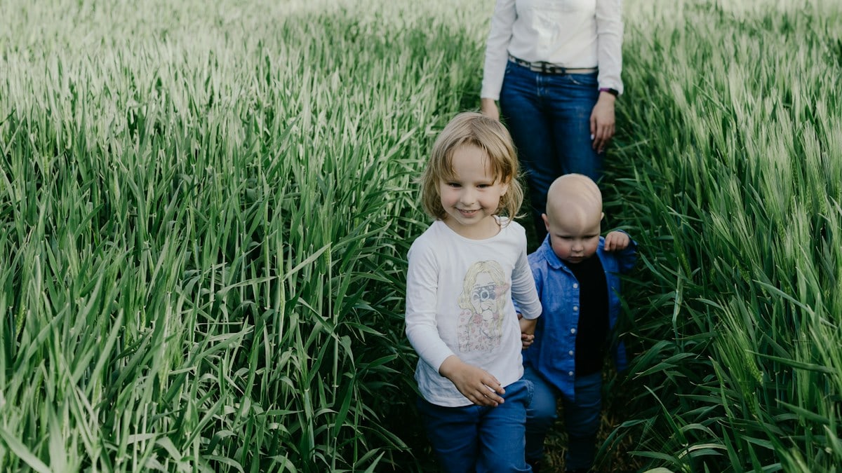 girl in white long sleeve shirt and blue denim jeans sitting on green grass field during